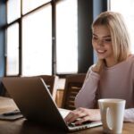 A woman smiling and working on her laptop