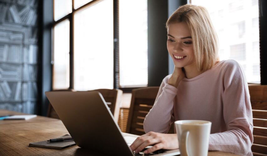 A woman smiling and working on her laptop